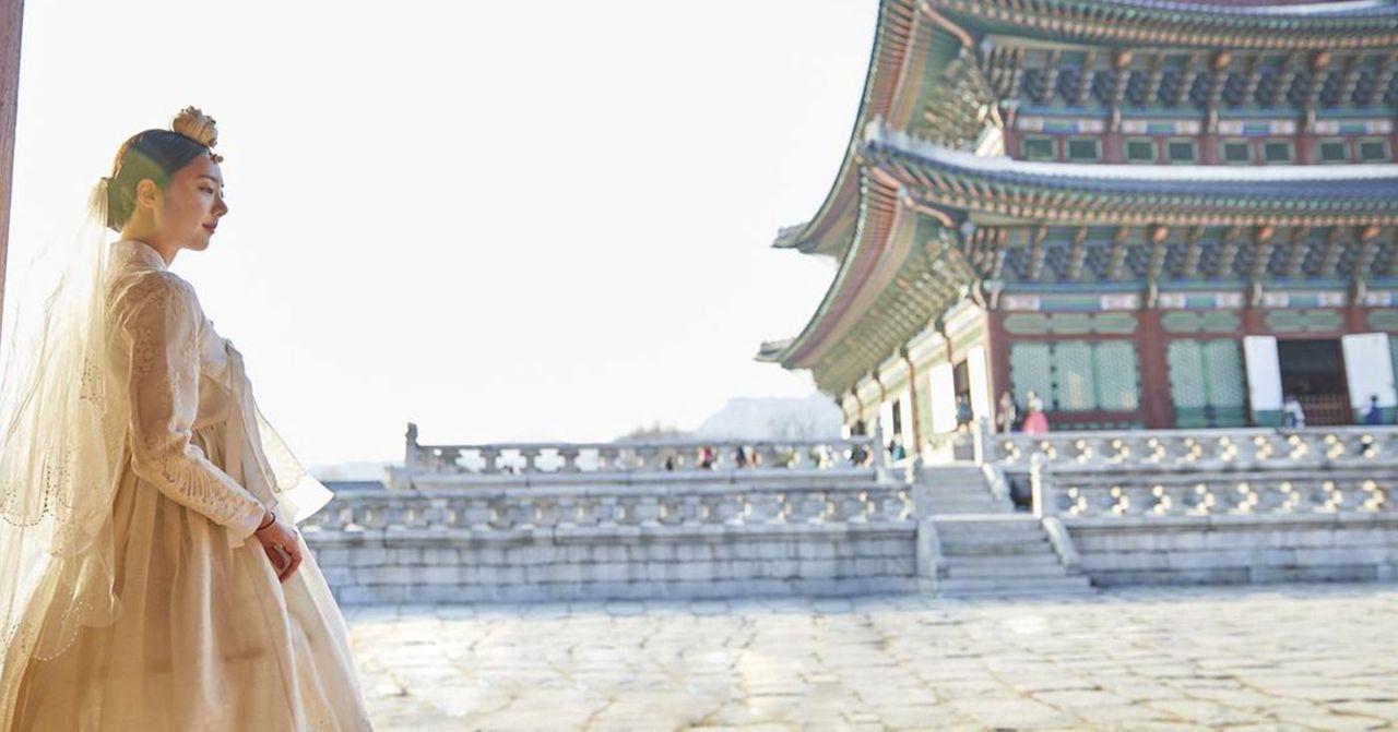 穿著韓服的遊客在夜晚的景福宮，背景是燈光昏黃的宮牆